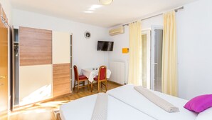 A hotel room with a bed, a desk with a chair, a TV, and a window with curtains. - Istriensonne 0039 - Ferienwohnung Vilic-S1 (Medulin)