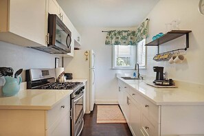 A compact kitchen with a stove, microwave, oven, and sink. - Spacious Beach Bungalow: Steps to Beach & Downtown (Lake Worth)