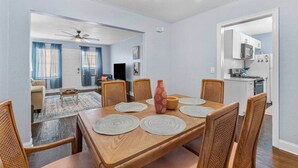 Un coin repas avec une table en bois, six chaises et un ventilateur de plafond.