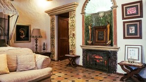 A room with a checkered floor, a sofa, a fireplace, and framed pictures on the wall. - Boutique Hotel Casa Cid de León (Oaxaca)