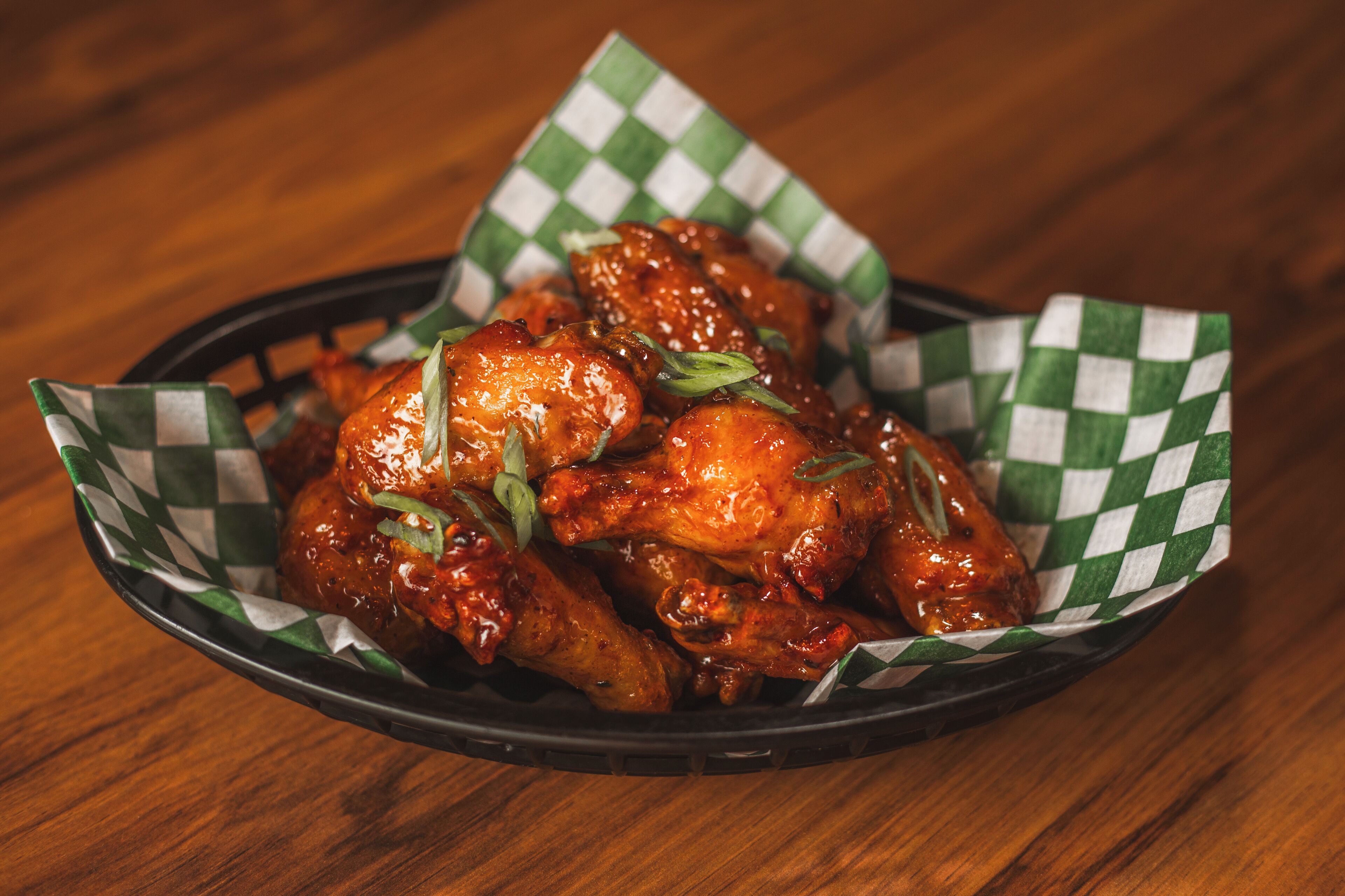 A basket of chicken wings on a wooden table.