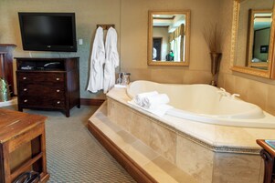 A bathroom with a large bathtub, a television mounted on the wall, and a mirror above the bathtub.