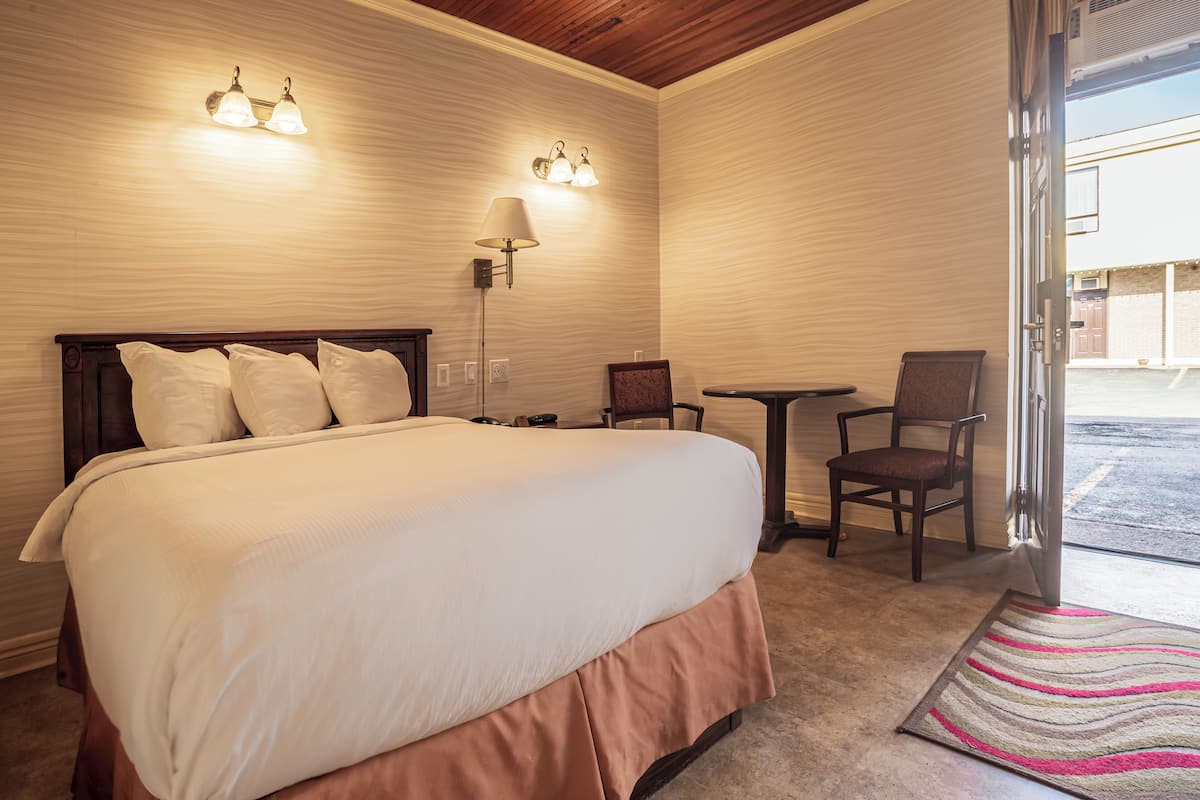 A hotel room with a large bed, two wall-mounted lights, a desk with a chair, and a view of the outside.
