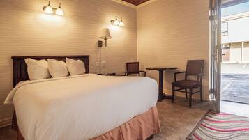 A hotel room with a large bed, two wall-mounted lights, a desk with a chair, and a view of the outside.