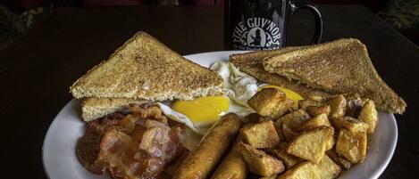 A plate of breakfast food including toast, eggs, bacon, sausages, and fried potatoes.
