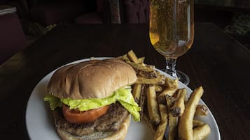 A plate with a burger and fries, and a glass of beer on a table.
