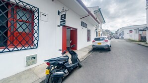 Une vue de rue avec un bâtiment blanc doté d’une porte rouge et d’une enseigne.