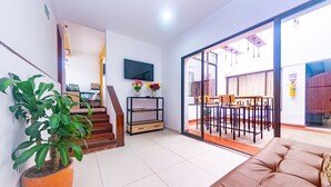 Un salon moderne comprenant un canapé, un escalier, un téléviseur à écran plat et un coin repas avec une table et des chaises.