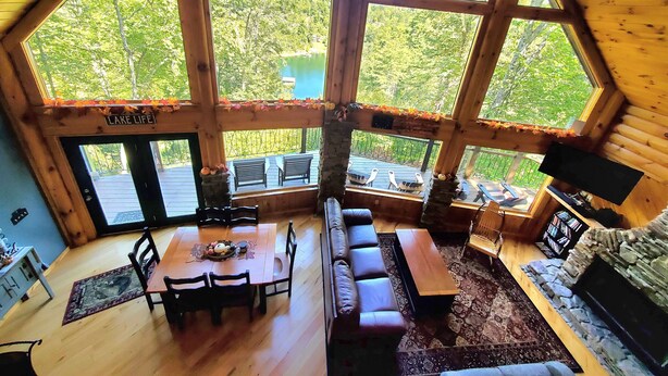A spacious cabin with a large dining area, a cozy seating area, and a view of a lake.