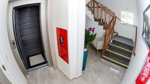 Un escalier avec des rampes en bois et des marches noires ornées de bandes jaunes.