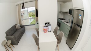 Un espace de vie compact comprenant un coin cuisine, un coin repas et un canapé.