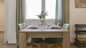 A dining table set for six with chairs, a vase with a plant, and a wine bottle.