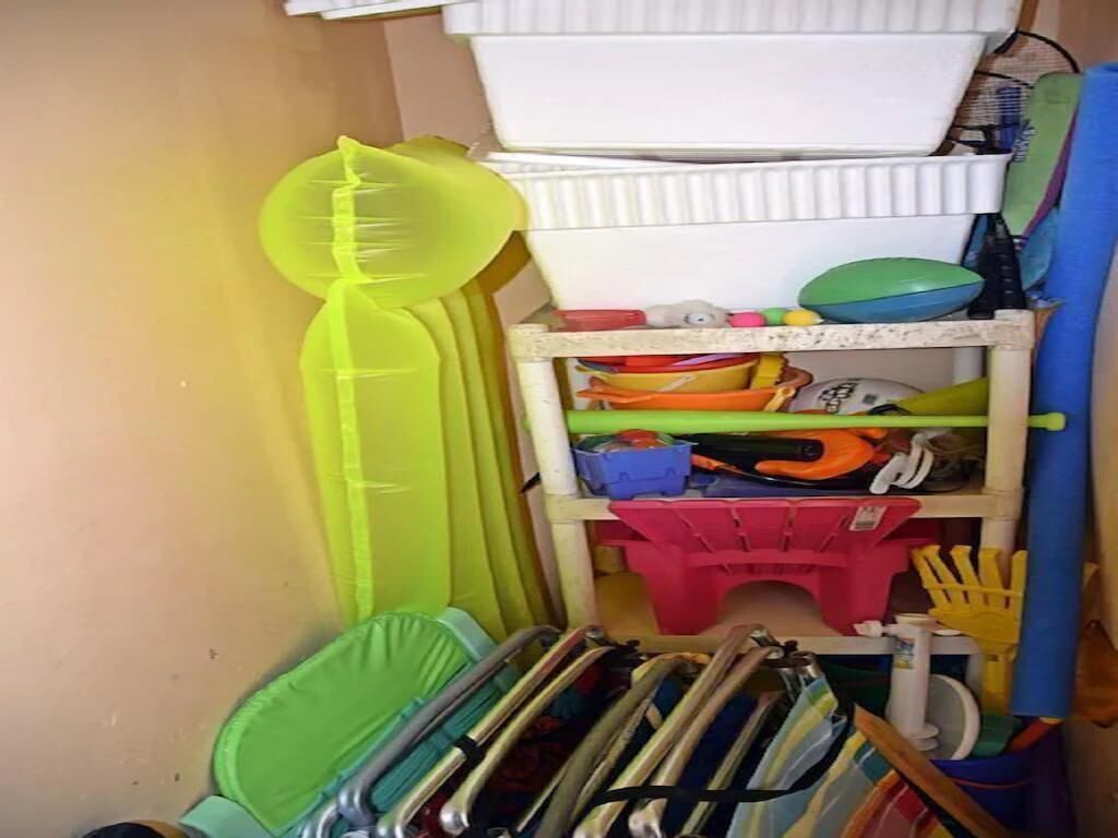 Un'area di stoccaggio con scaffali che contengono diversi oggetti, tra cui contenitori di plastica, prodotti per la pulizia e attrezzi.
