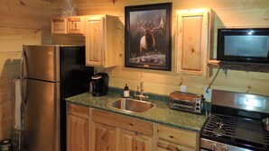 Une cuisine avec des meubles de rangement en bois, un réfrigérateur, un four à micro-ondes, un grille-pain et un évier.