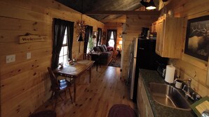 L’intérieur d’une cabane en bois comprend un coin repas, une cuisine et un espace de vie.