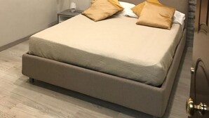 Ein modernes Schlafzimmer mit einem großen Bett, einem Nachttisch, einer Klimaanlage und einer strukturierten Wand.