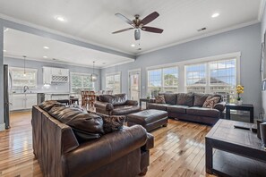 A spacious living area with leather sofas, a dining table, and a kitchen in the background. - Dream house in NMB, short walk to the ocean (North Myrtle Beach)
