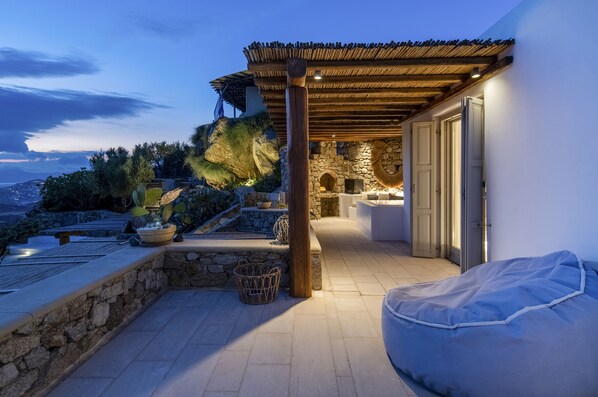 A rooftop terrace with stone walls, a wooden pergola, and a seating area.