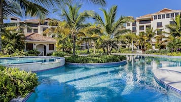 Una piscina al aire libre, sombrillas, sillones reclinables de piscina