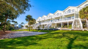 A beachfront hotel with multiple balconies, a central courtyard, and a sandy walkway. - 30A Retreat, Walk 250 yds to Beach, Pool, Hot Tub, 4 Bikes, Umbrella, Chairs! (Walton County)