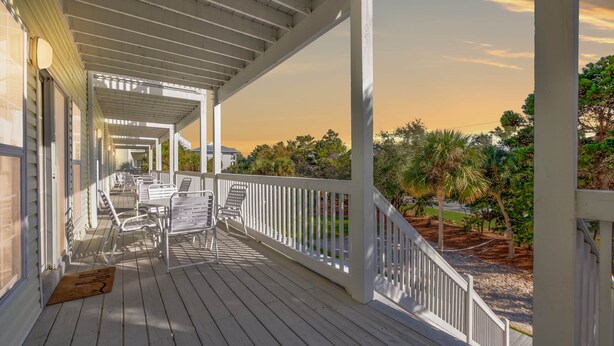 A covered outdoor area with a wooden deck, white railings, and metal chairs. - 30A Retreat, Walk 250 yds to Beach, Pool, Hot Tub, 4 Bikes, Umbrella, Chairs! (Walton County)
