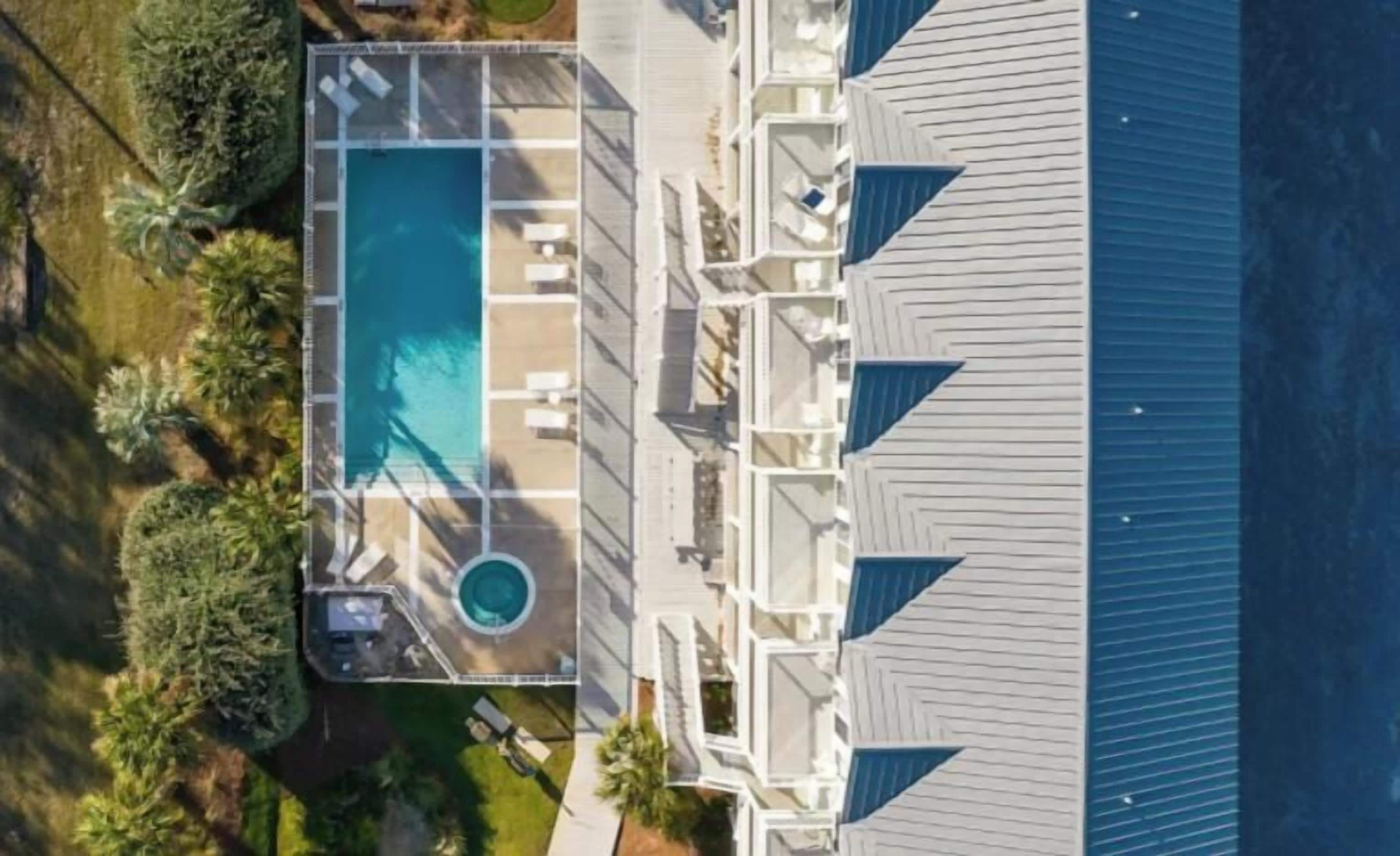 Een luchtendbeeld van een hotel met een zwembad, meerdere balkons en een overdekt buitengebied.