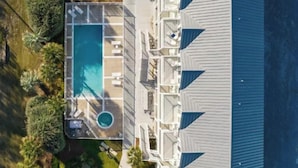 Eine Vogelperspektive zeigt ein Hotel mit einem Schwimmbad, mehreren Balkonen und einem überdachten Außenbereich.