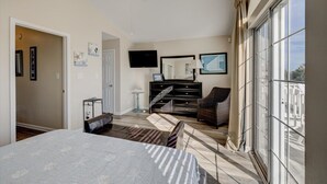 A bedroom with a bed, a dresser, a chair, a TV, and a large window. - 30A Retreat, Walk 250 yds to Beach, Pool, Hot Tub, 4 Bikes, Umbrella, Chairs! (Walton County)
