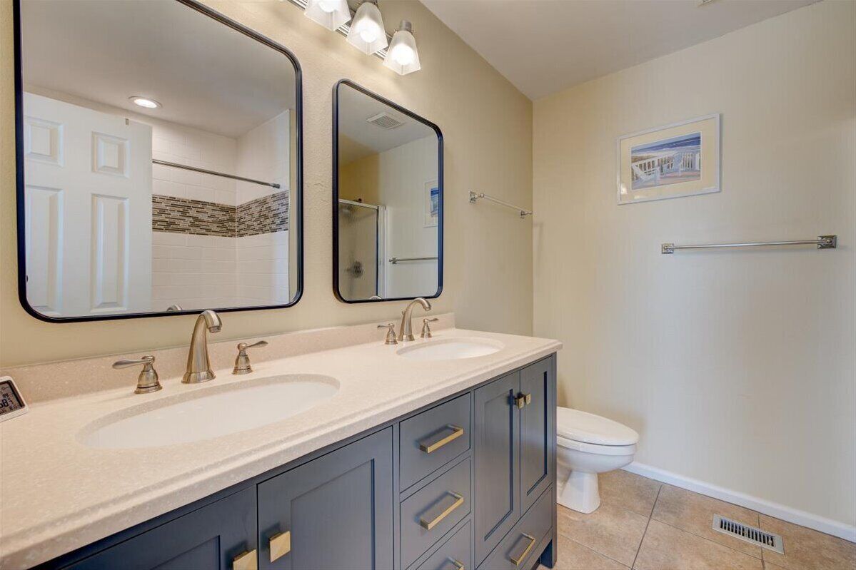 Une salle de bain avec deux lavabos, des toilettes et une douche.
