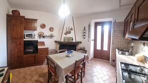 A compact kitchen with wooden cabinets, a microwave, a stove, and a dining table with chairs.