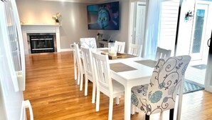 A dining area with a white table and chairs, a fireplace, and a television on the wall. - Toddler Friendly, toys, boardwalk, beach, downtown, POOL, & clean! You get ALL!  (Point Pleasant Beach)
