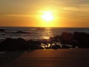 A sunset over the ocean with rocks in the foreground. - Exclusive Private Villa Caribbean Estates (Port Edward)