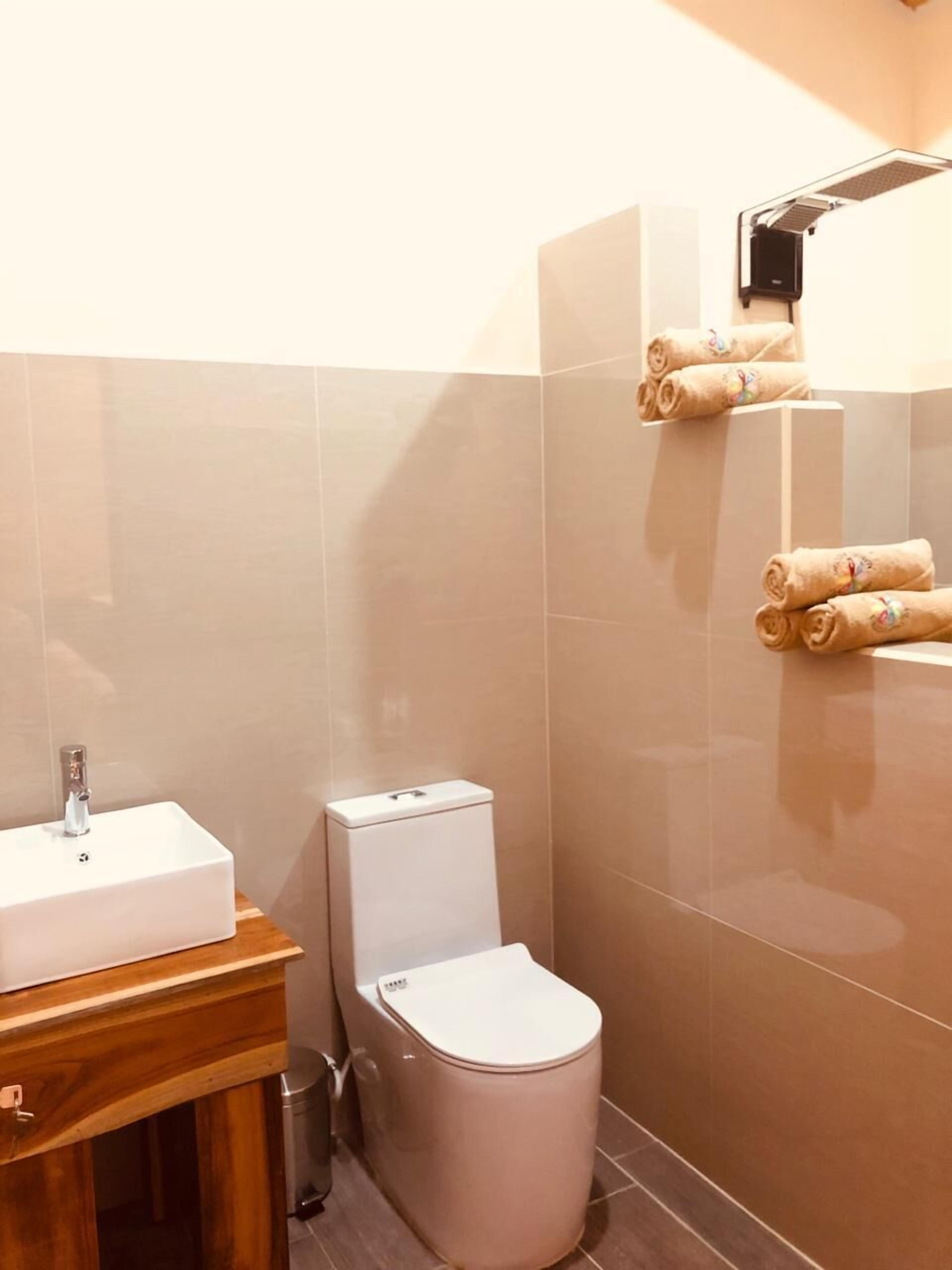 A bathroom with a toilet, sink, and a towel rack with towels.