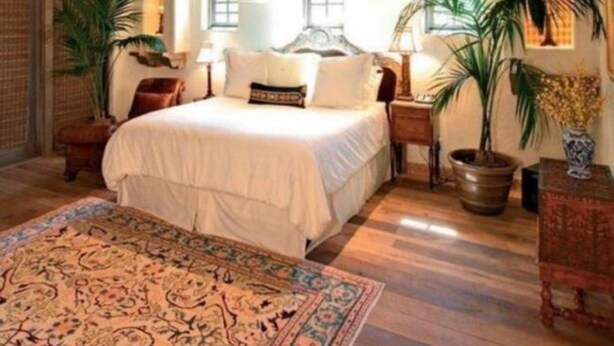 A bedroom with a wooden ceiling, a large bed, a patterned rug, and potted plants. - White Sands Hotel (Quepos)