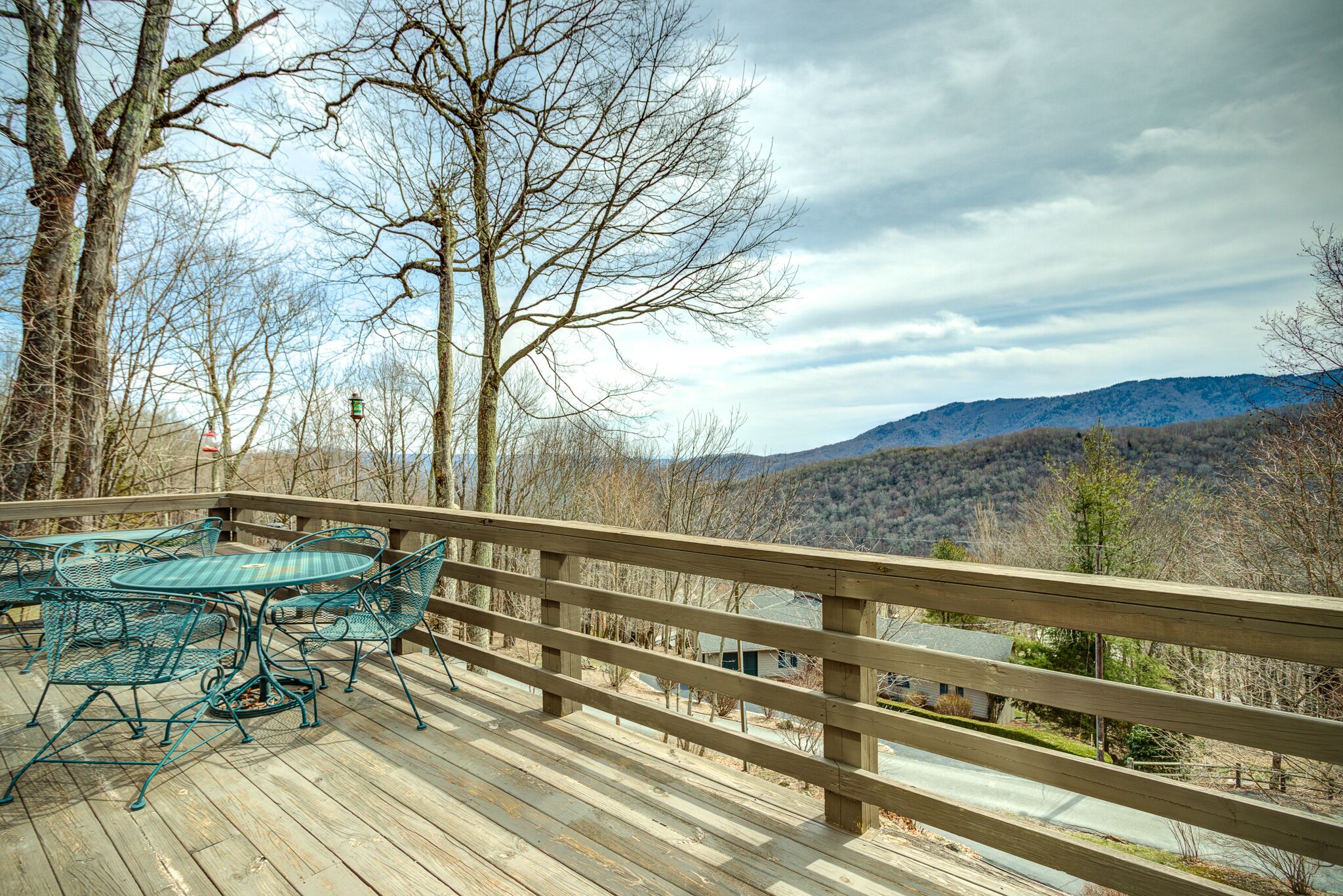 Eine Holzterrasse mit Metallmöbeln und Blick auf die Berge.