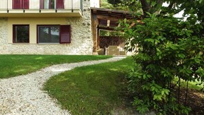 Ein Steinhaus mit einem Kiesweg, der zu einer hölzernen Pergola führt.