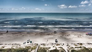Una playa con arena, algunos vehículos y cielo despejado.
