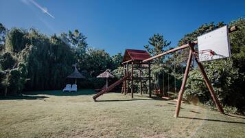 Un parque infantil con columpios, tobogán y un aro de baloncesto.