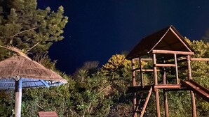 A night scene with a wooden play structure and lounge chairs under a thatched roof. - Dunas del Este (Punta Colorada)