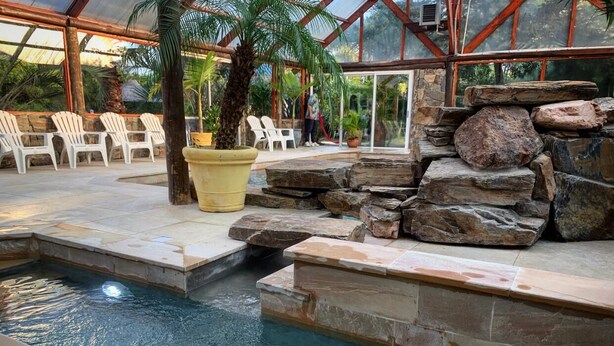 An indoor pool area with stone steps, lounge chairs, and a glass-enclosed structure. - Dunas del Este (Punta Colorada)