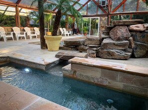 An indoor pool area with stone steps, lounge chairs, and a glass-enclosed structure. - Dunas del Este (Punta Colorada)