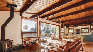 A spacious living area with a large wooden ceiling, a fireplace, and a view of the outdoors through large windows. - Hidden Oasis Hot Tub-Disney Train Track. (Julian)