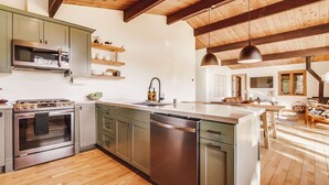 A modern kitchen with stainless steel appliances, wooden beams, and a central island. - Hidden Oasis Hot Tub-Disney Train Track. (Julian)