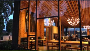 Un restaurante moderno con amplios ventanales, interior de madera y luminarias originales.