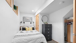 A bedroom with a bed, a dresser, a mirror, and a wall-mounted picture. - Black Butte Ranch A-Frame · Pools, Golf, Sleeps 8 (Sisters)