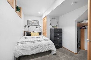 A bedroom with a bed, a dresser, a mirror, and a wall-mounted picture. - Black Butte Ranch A-Frame · Pools, Golf, Sleeps 8 (Sisters)