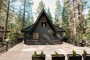 Una cabaña de techo triangular rodeada de altos árboles.