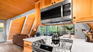 Une cuisine moderne avec des meubles en bois, des appareils électroménagers en acier inoxydable et une grande fenêtre donnant sur l’extérieur.