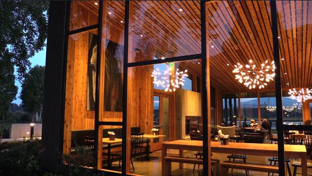 Un restaurant moderne doté de grandes fenêtres, d’un décor intérieur en bois et de luminaires originaux.