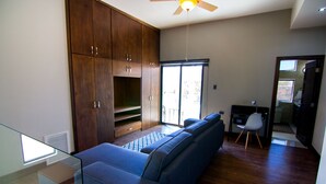 A modern living room with a blue sofa, wooden cabinets, and a ceiling fan. - Amplio departamento, con la mejor ubicación en la ciudad (Chihuahua)